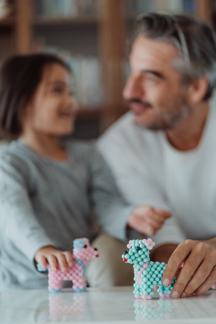 Father and daughter enjoying creative play together with beaded toys indoors.